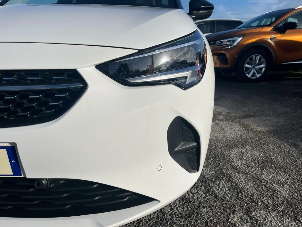 Gros plan sur l'avant droit blanc d'une Opel Corsa 2022, mettant en valeur le phare et la calandre noire.