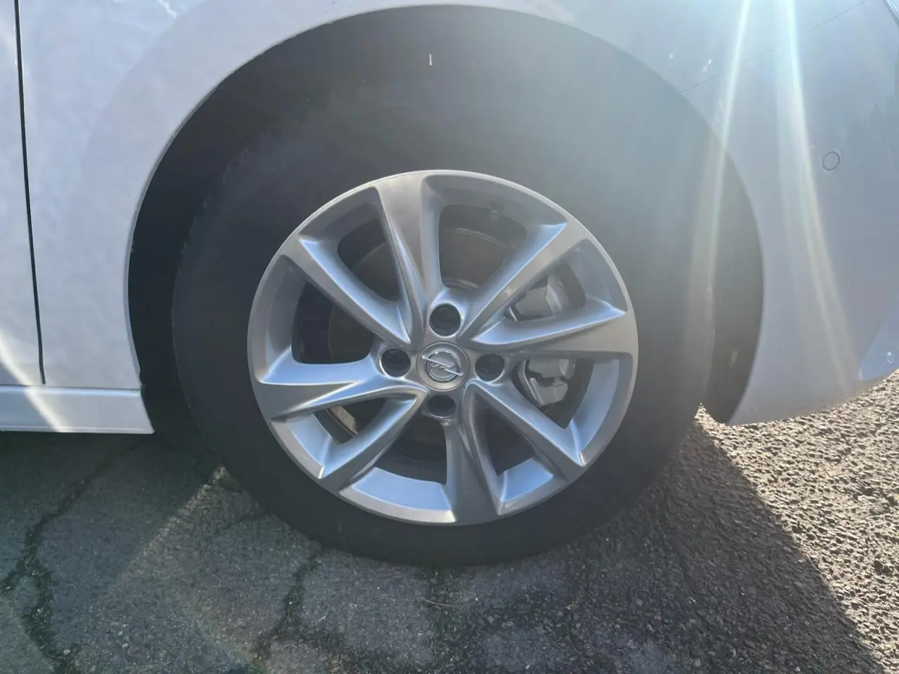 Gros plan sur la roue avant droite avec jante argentée de l'Opel Corsa blanche 2022, détails du pneu et jante visibles.