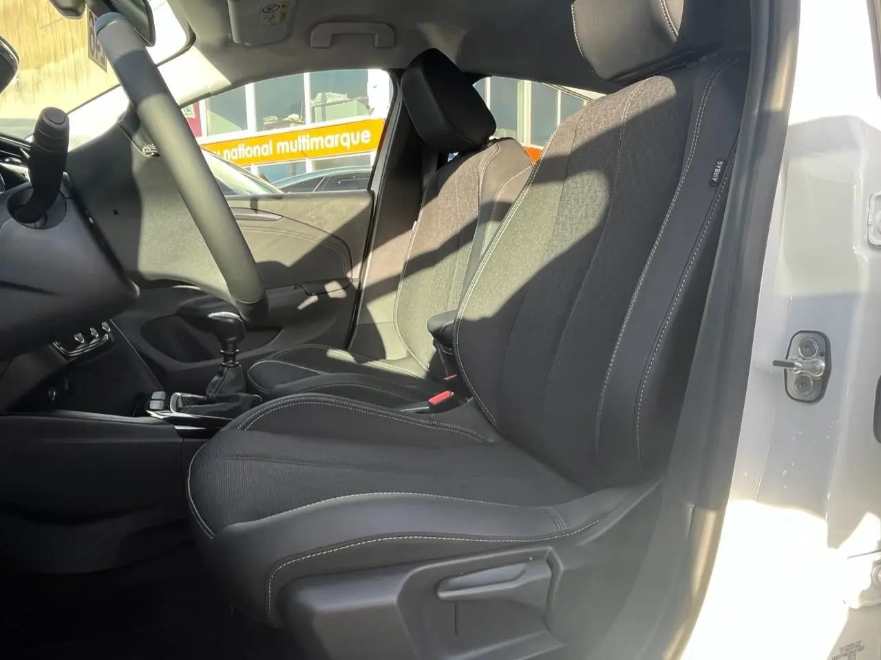Vue intérieure côté conducteur de l’Opel Corsa blanc 2022, sièges noirs avec surpiqûres blanches visibles.