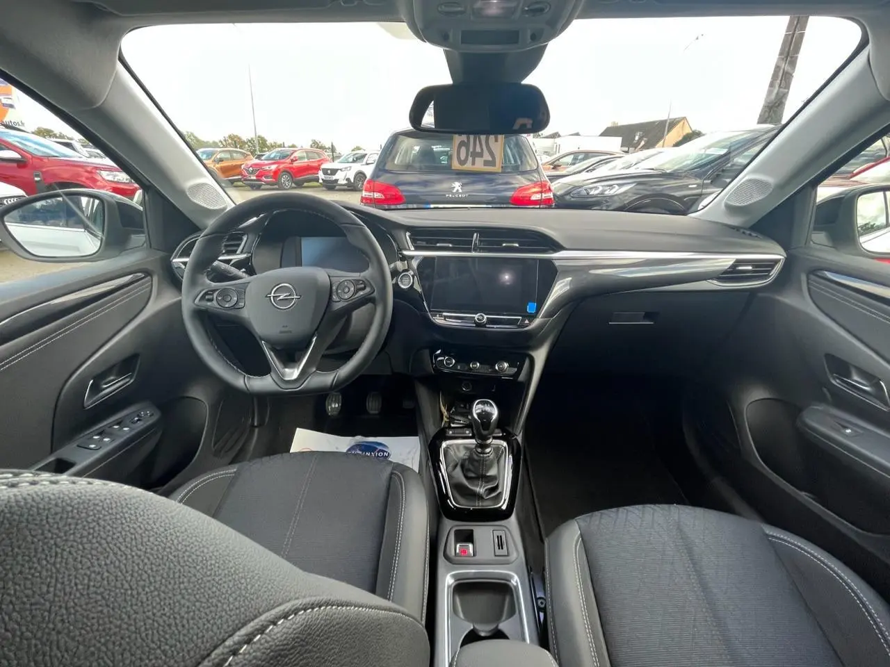 Vue intérieure avant de l’Opel Corsa blanche 2022, montrant le tableau de bord et la console centrale avec boîte manuelle.