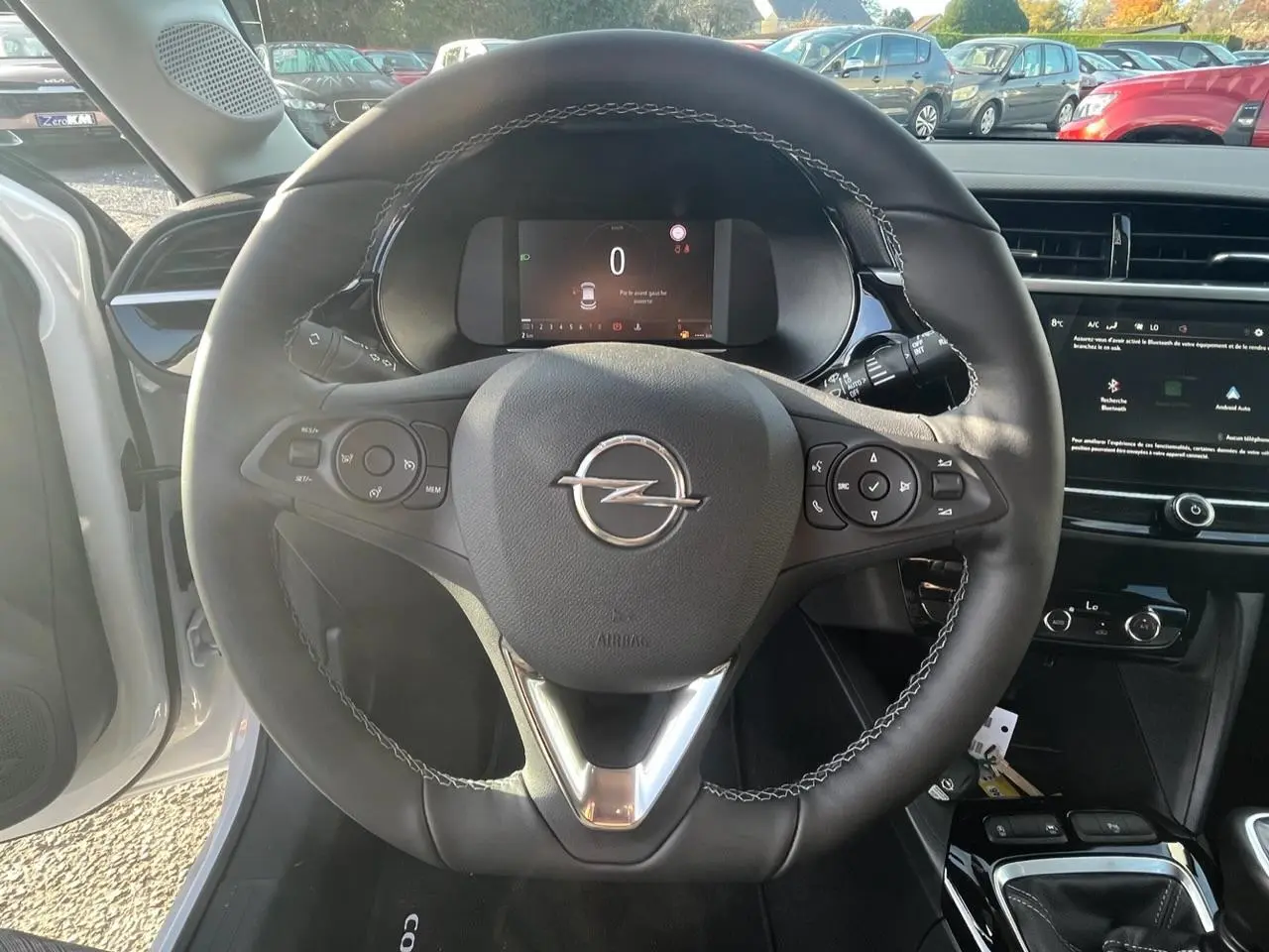 Vue intérieure centrée sur le volant noir de l'Opel Corsa blanc avec tableau de bord digital et écran tactile.