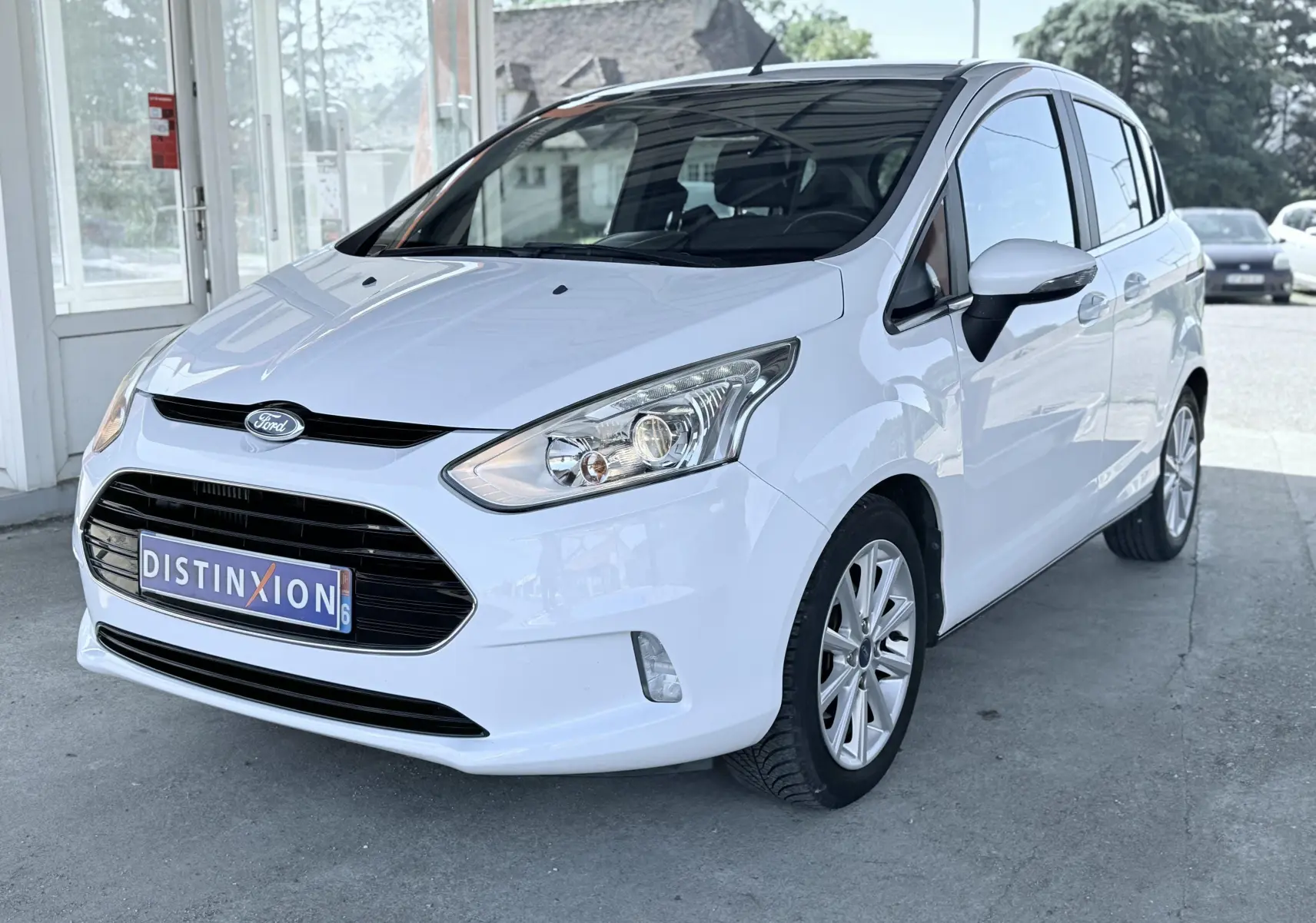 Ford B-MAX blanc vue 3/4 avant droit, avec calandre noire et jantes alliage visibles, stationné en extérieur.