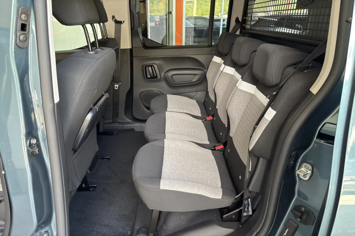 Vue latérale intérieure des sièges arrière gris et noirs du Citroën Berlingo Kiama Blue avec grille de séparation amovible.