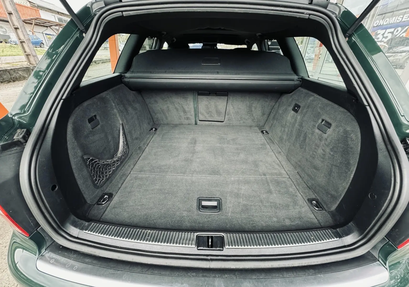 Coffre ouvert d'une Audi S4 Avant verte de 2004, montrant un espace de chargement propre et bien fini.