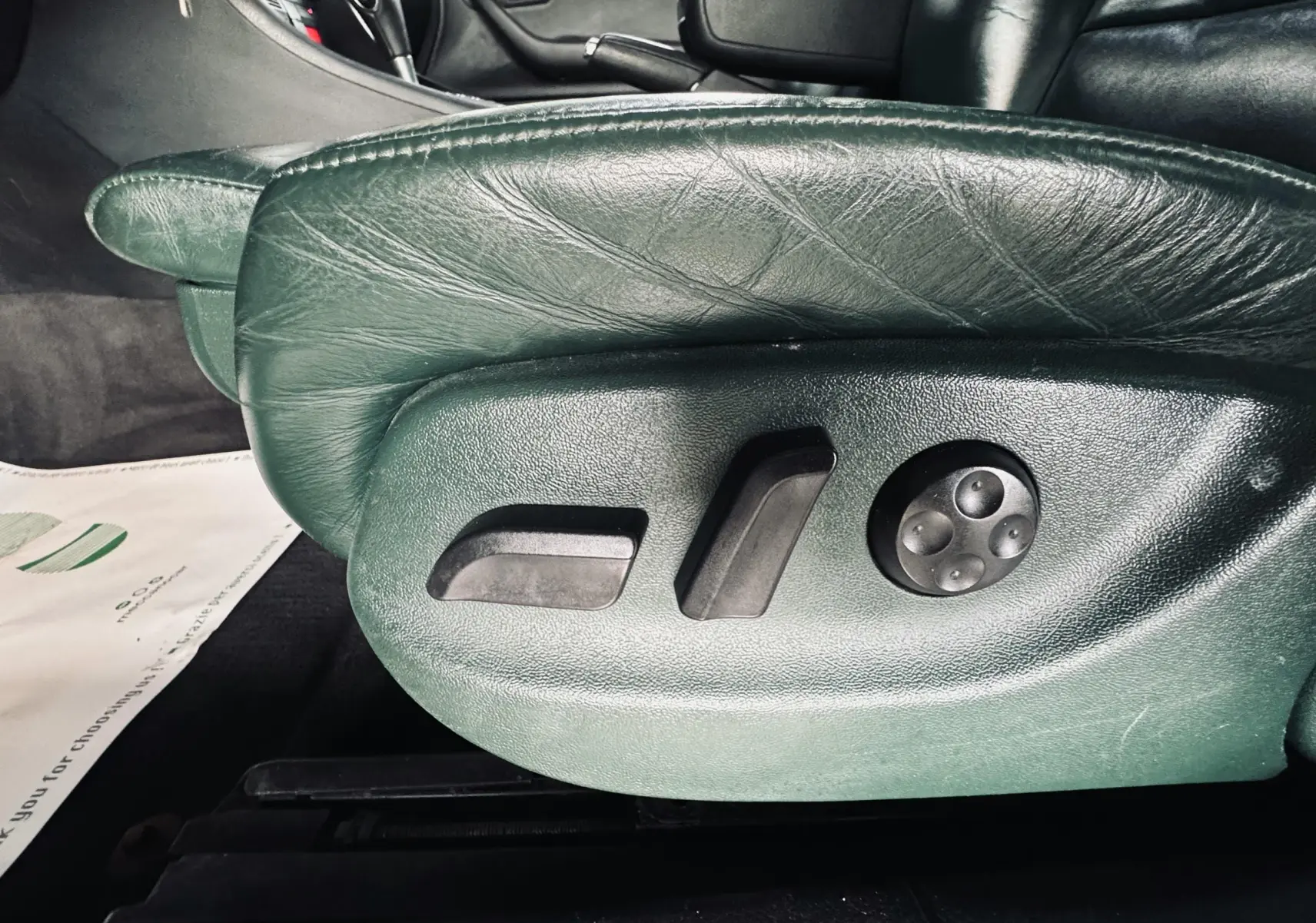 Gros plan sur les commandes électriques du siège en cuir vert foncé de l'Audi S4 Avant 2004, côté conducteur.