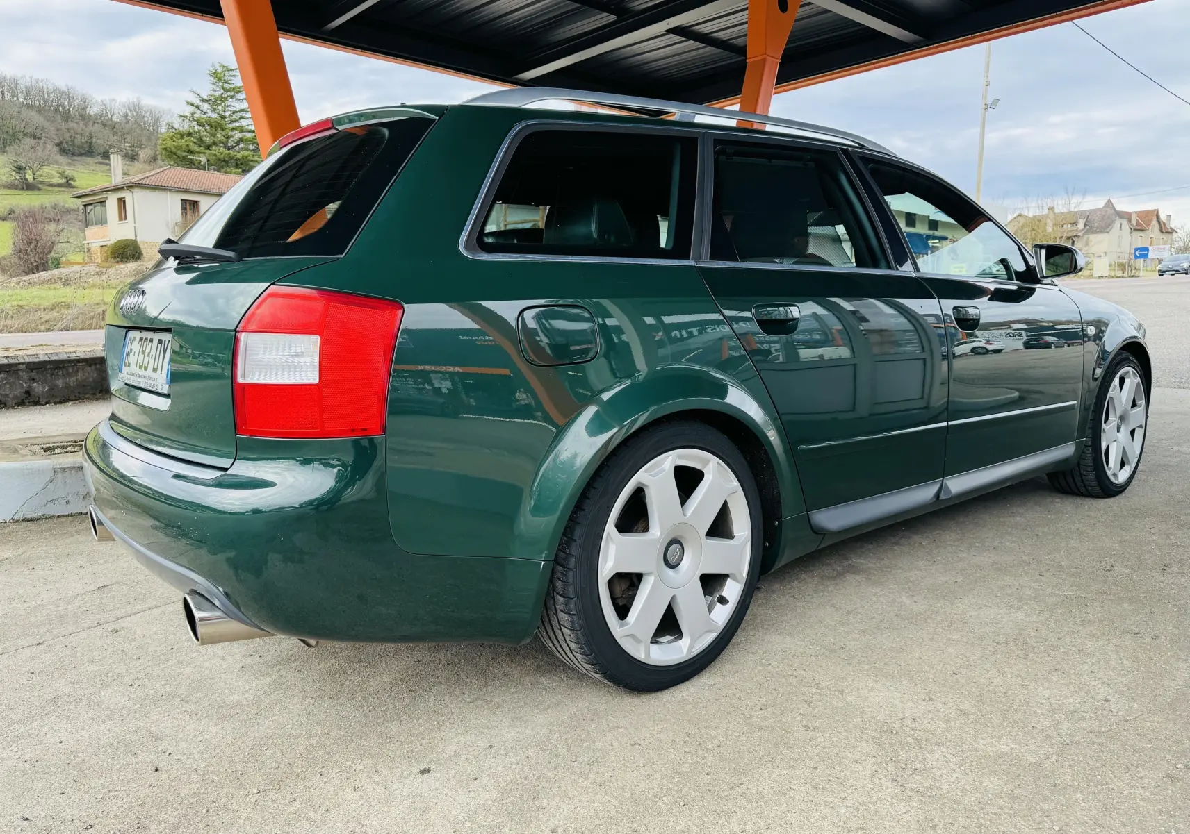 Vue 3/4 arrière droite d'une Audi S4 Avant 2004 verte avec jantes alliage et échappement sport visible.