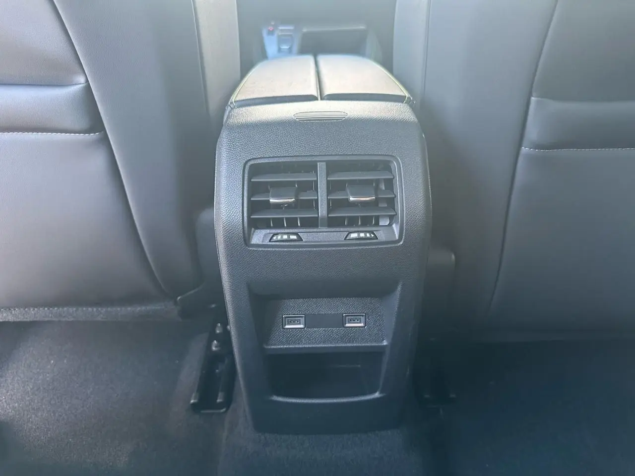 Vue rapprochée des aérateurs arrière et des deux prises USB C sur la console centrale noire du Peugeot 308 blanc Okenite.