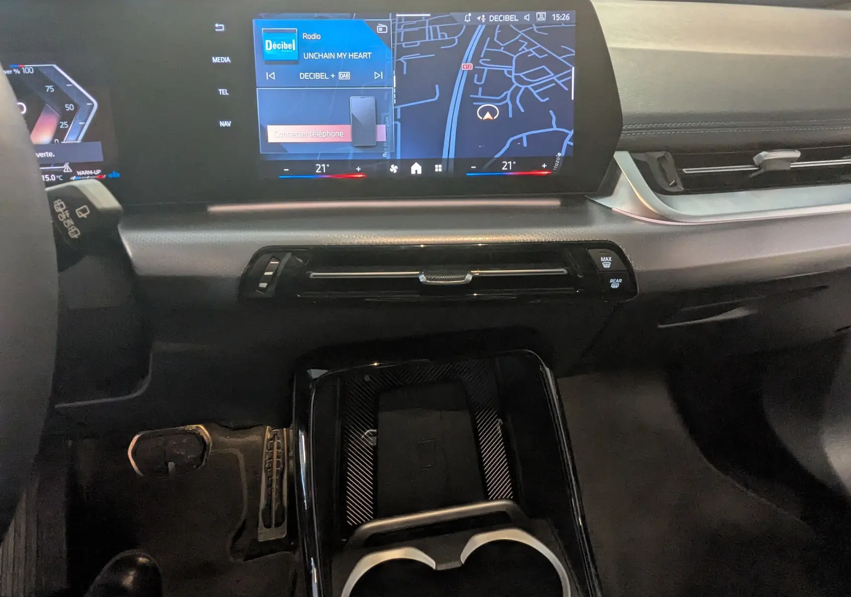 Tableau de bord noir de BMW X1 2025 avec écran tactile large affichant navigation et radio, console centrale moderne.