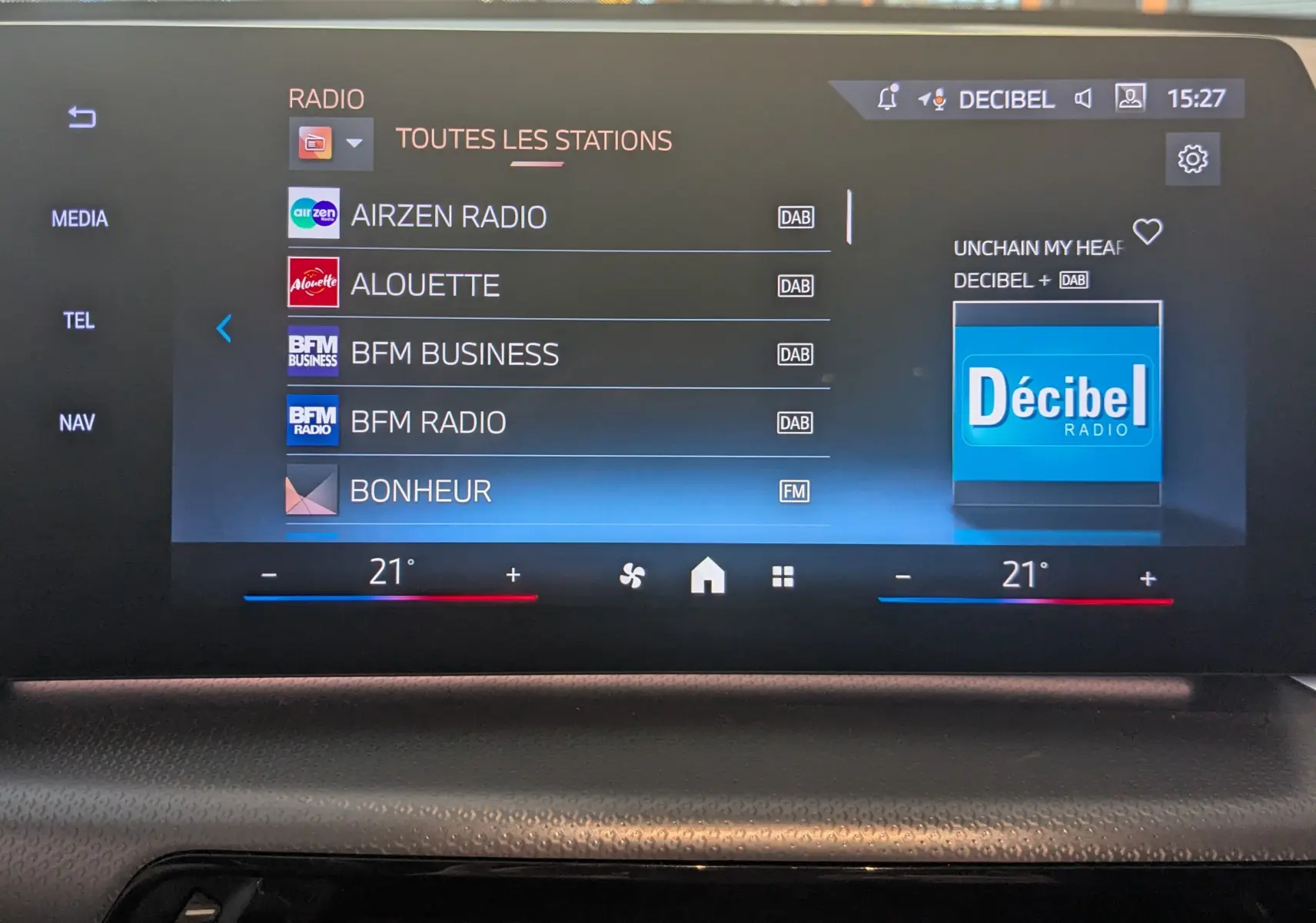 Écran tactile central du BMW X1 noir 2025 affichant les stations radio avec interface moderne et réglage de température à 21°C.