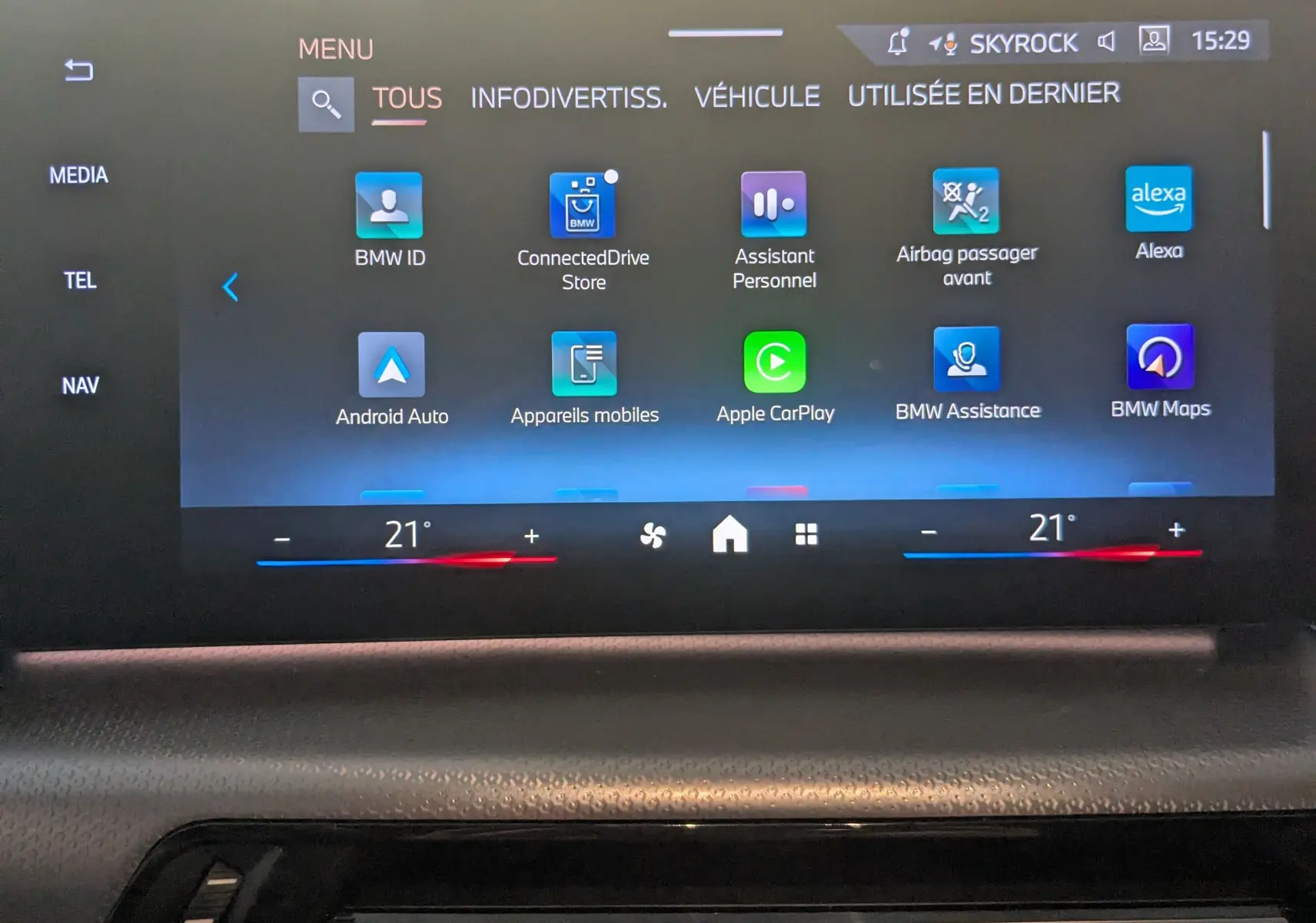 Écran tactile central du BMW X1 noir, affichant le menu principal avec options connectées et réglages climatisation.