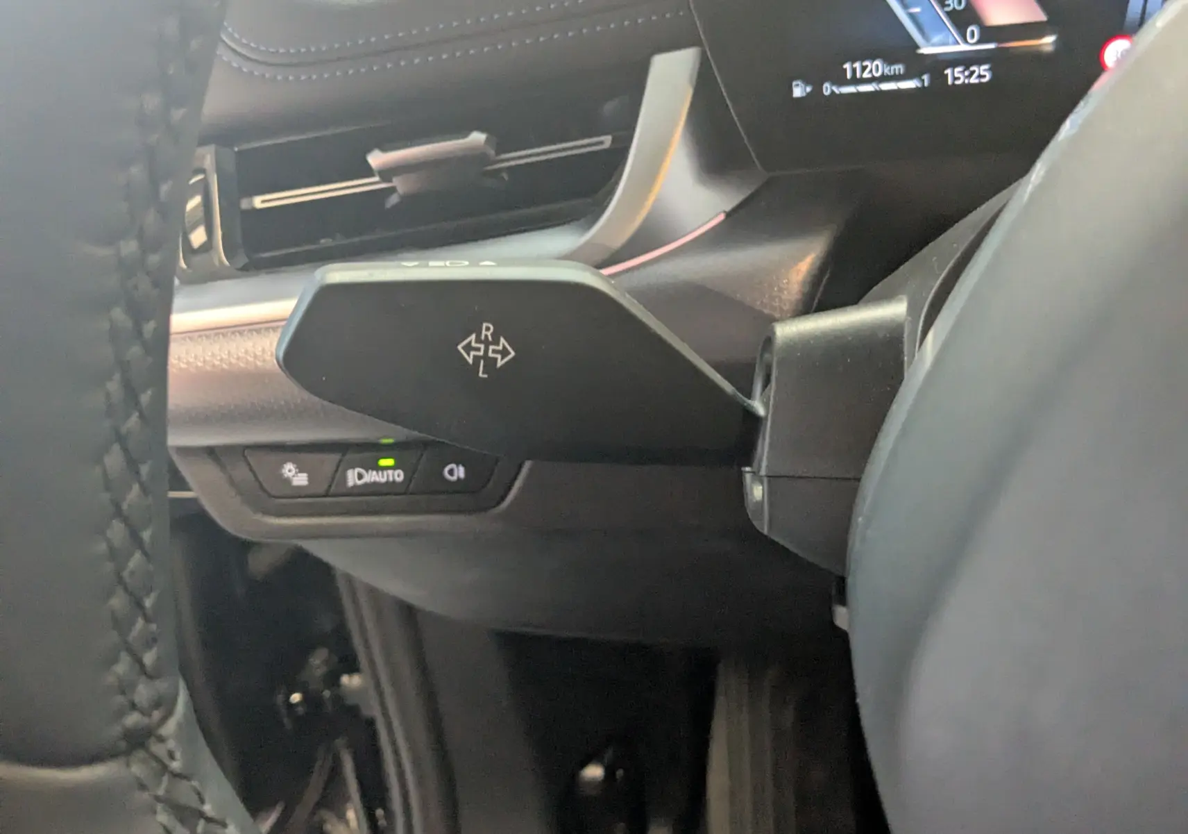 Gros plan sur la commande de clignotant à gauche du volant dans l’habitacle noir du BMW X1 2025.