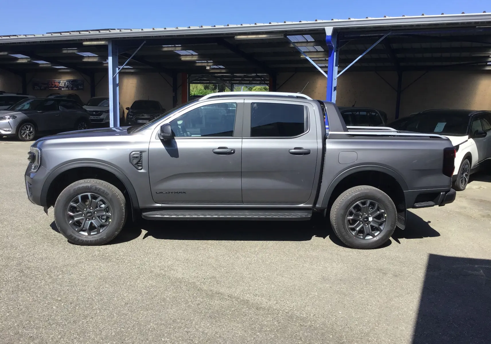 Vue latérale droite d'un Ford Ranger Double Cabine gris carbone Wildtrak 2025 avec rideau de plateau et marchepied.