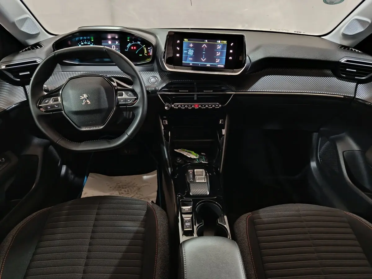 Intérieur du Peugeot 208 électrique 2023 vu de face, tableau de bord moderne avec écran tactile et volant cuir multifonctions.