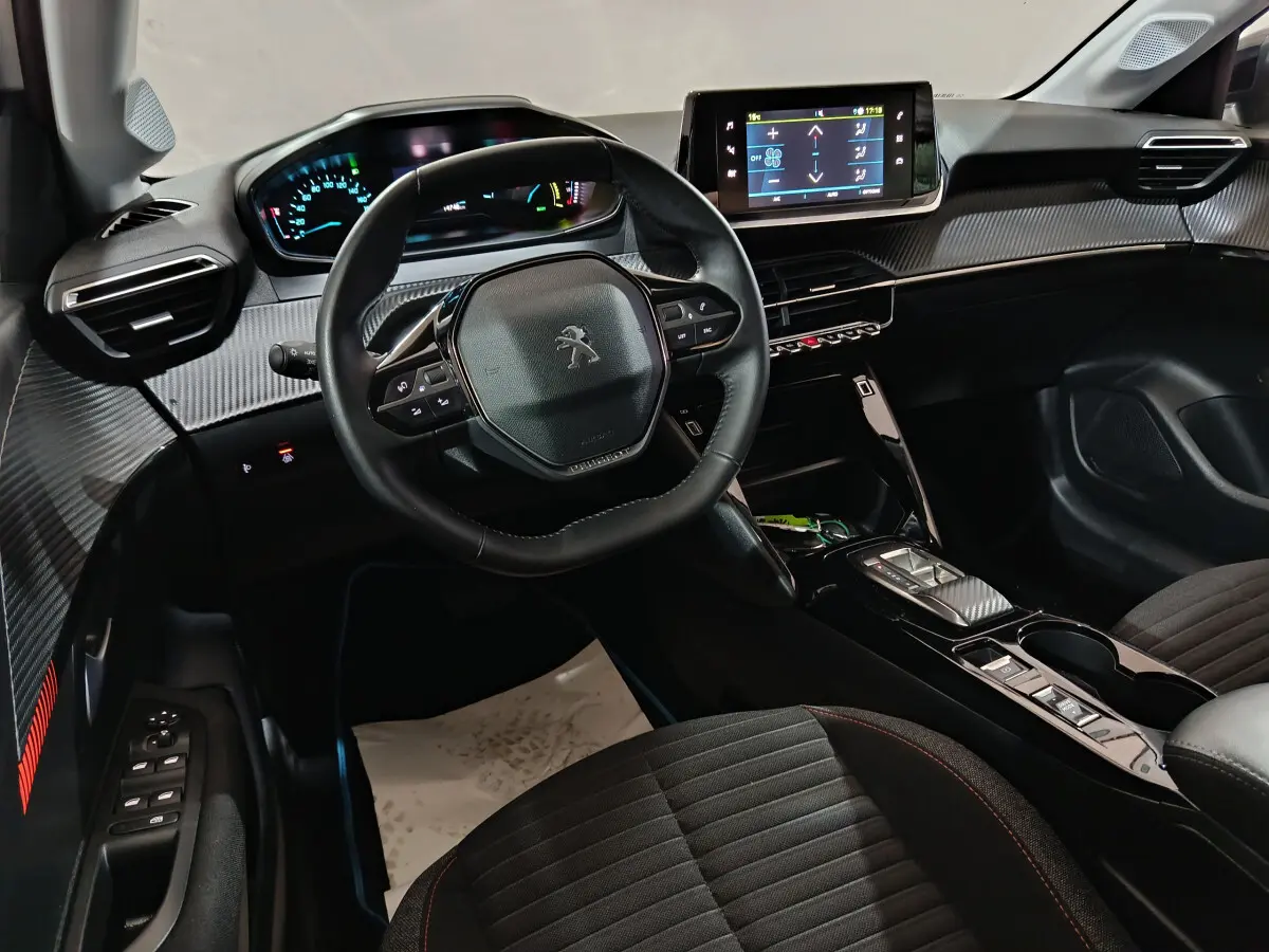 Intérieur de la Peugeot 208 électrique 2023 vu côté conducteur, tableau de bord moderne avec écran tactile central.