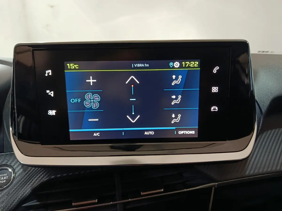 Écran tactile central allumé du tableau de bord d'une Peugeot 208 électrique blanche, vue intérieure frontale.