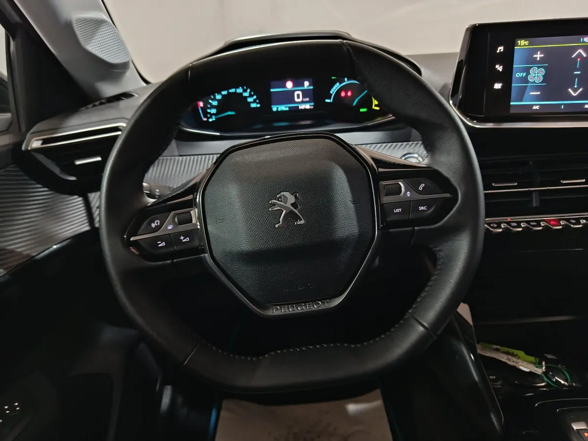 Vue rapprochée du volant cuir noir et du tableau de bord digital de la Peugeot 208 électrique 2023, intérieur moderne.