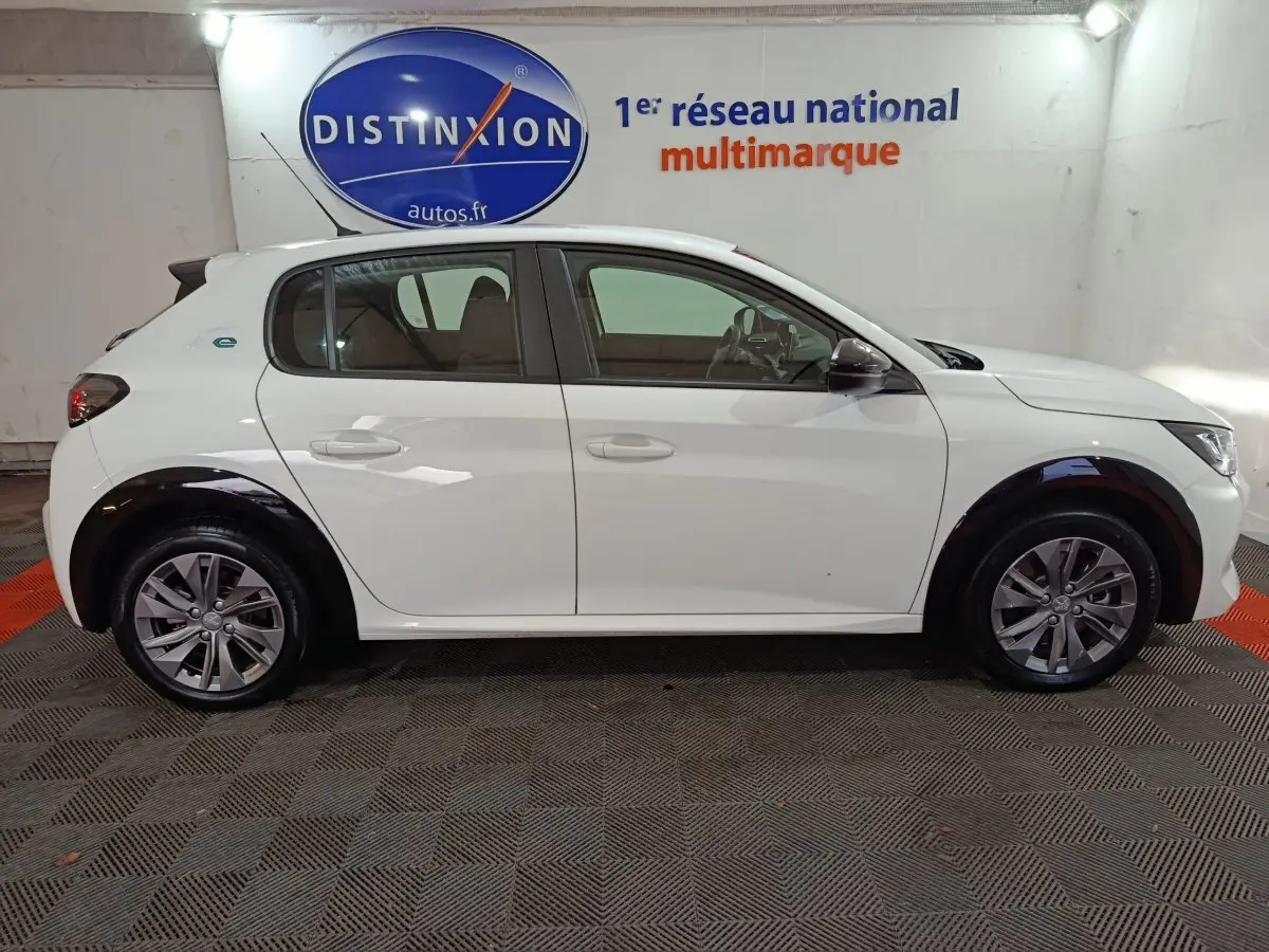Profil droit d'une Peugeot 208 électrique blanche 2023, avec jantes alliage et détails noirs contrastants sur les passages de roues.