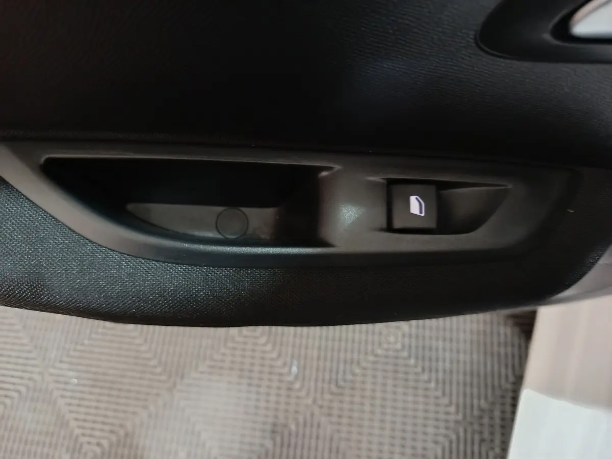 Bouton de verrouillage de porte noir sur panneau intérieur de porte d'une Peugeot 208 électrique blanche, vue rapprochée.