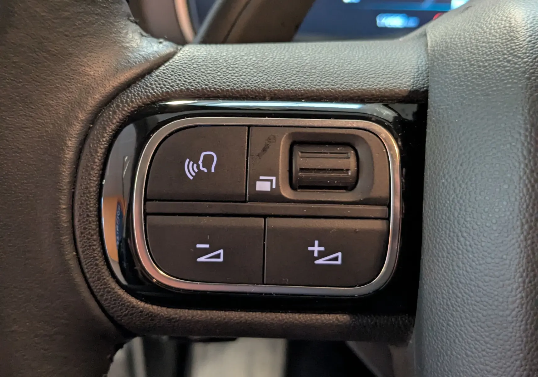 Gros plan sur les commandes de volume et de gestion d’appel sur le volant noir du Citroën C5 Aircross hybride 2025.