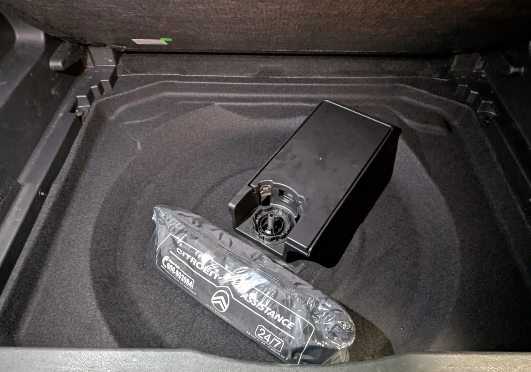 Coffre ouvert du Citroën C5 Aircross hybride noir 2025, vue plongeante sur rangement avec kit assistance emballé.