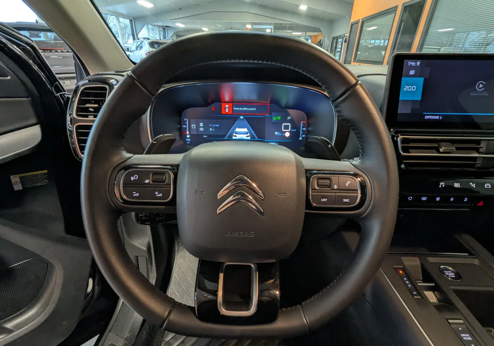 Vue intérieure centrée sur le volant cuir noir du Citroën C5 Aircross hybride 2025 avec tableau de bord digital et écran tactile.
