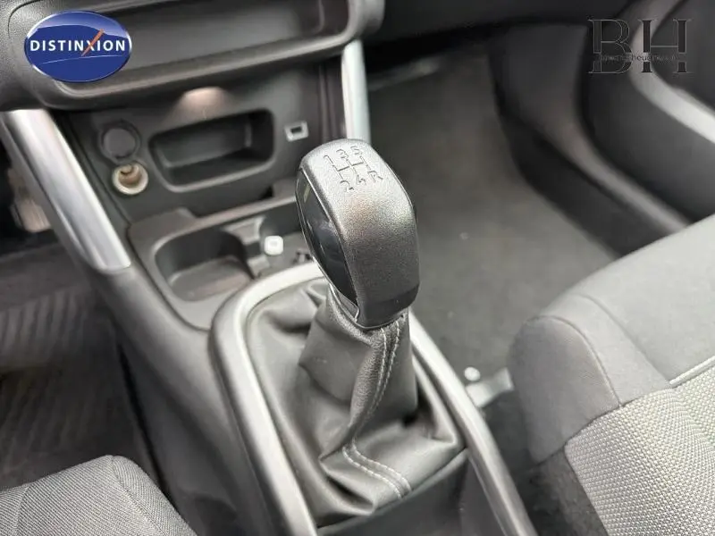 Gros plan sur le levier de vitesses manuel noir dans l'habitacle gris du Citroën C3 Aircross Natural White.