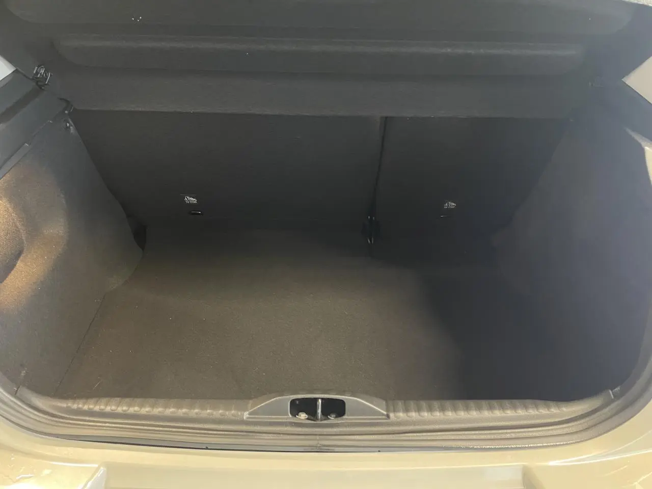 Coffre ouvert vu de face d’une Citroën C3 beige clair 2024, montrant l’espace de chargement vide.