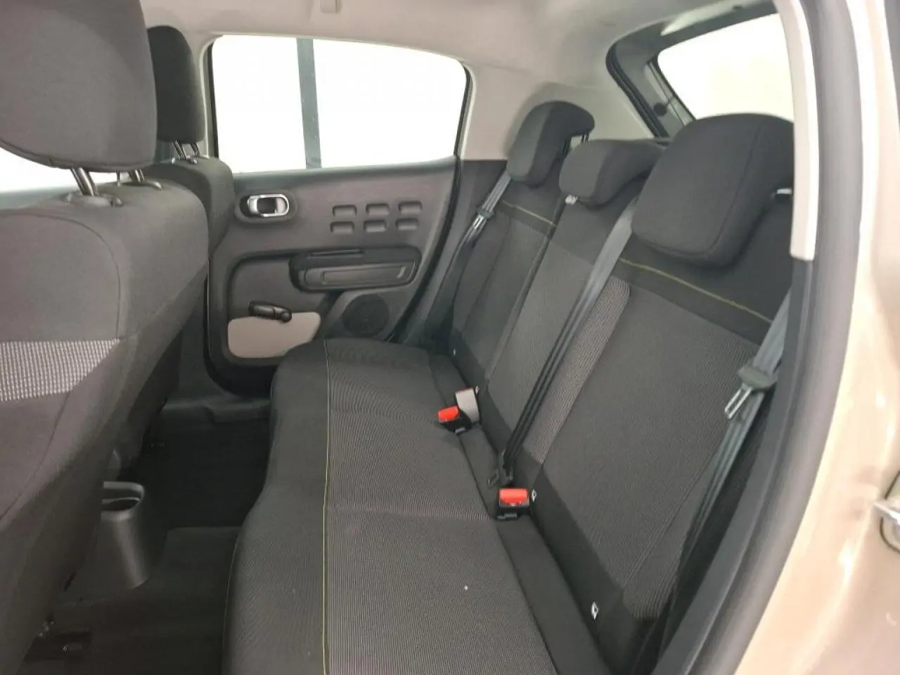 Vue intérieure côté droit de la banquette arrière noire avec surpiqûres jaunes d'une Citroën C3 beige clair 2024.