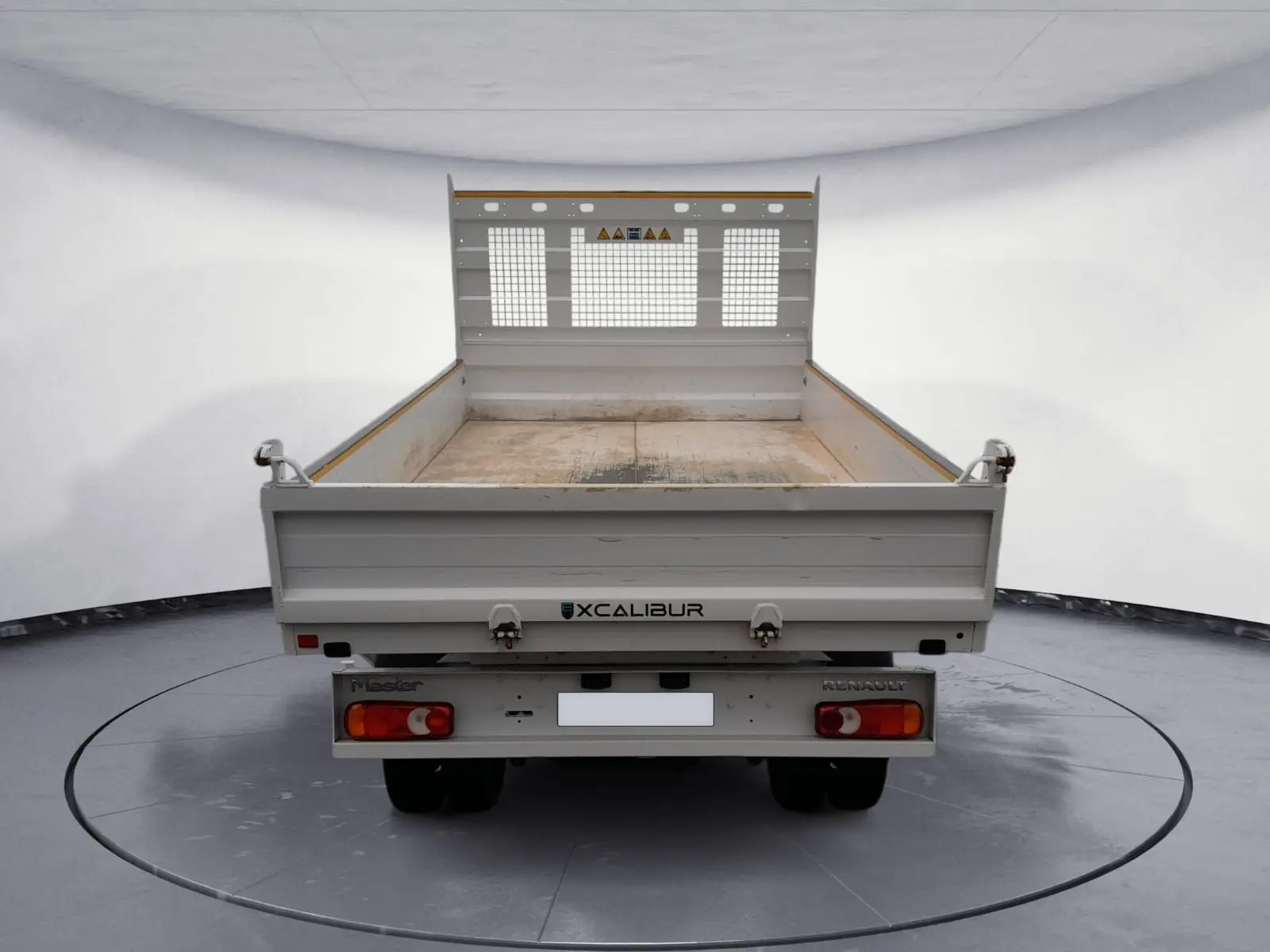 Vue arrière d'une benne blanche Renault Master 2024 avec plateau ouvert et grille de protection métallique.