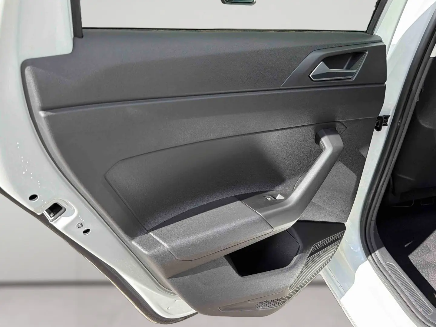 Vue rapprochée de la porte arrière gauche blanche d'une Volkswagen Polo 2025 avec garniture intérieure noire et commandes de vitre.