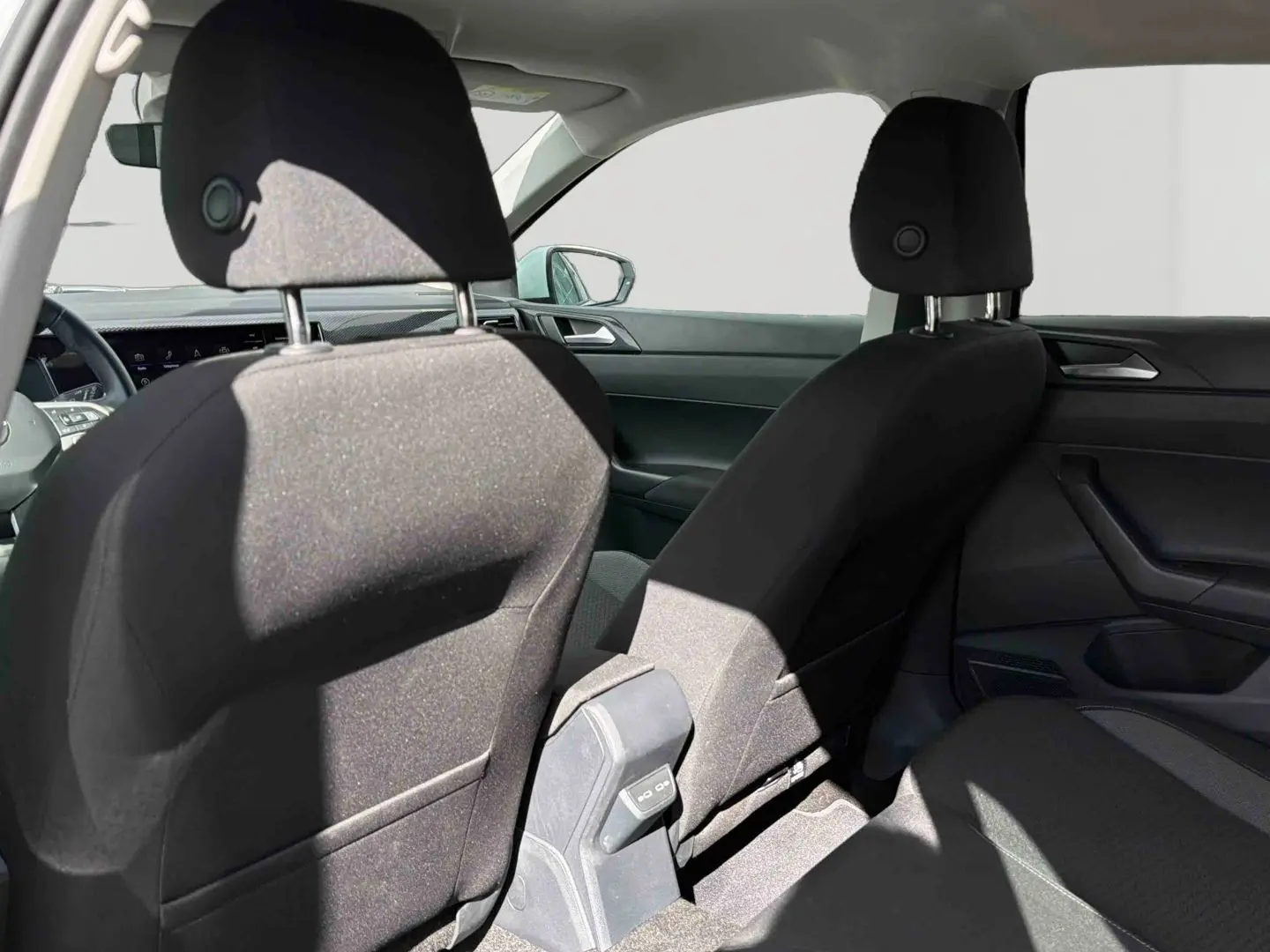Vue intérieure arrière montrant les sièges avant noirs et la console centrale d'une Volkswagen Polo blanche 2025.