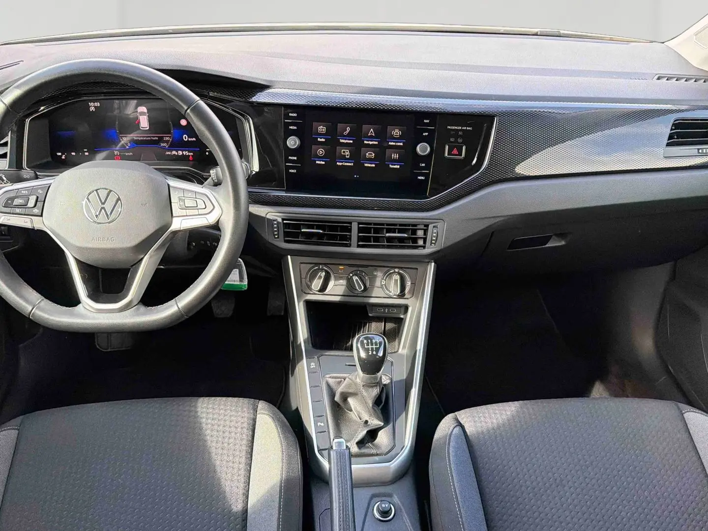 Vue intérieure avant de la Volkswagen Polo 2025, montrant le volant cuir, écran tactile et levier de vitesses manuel.