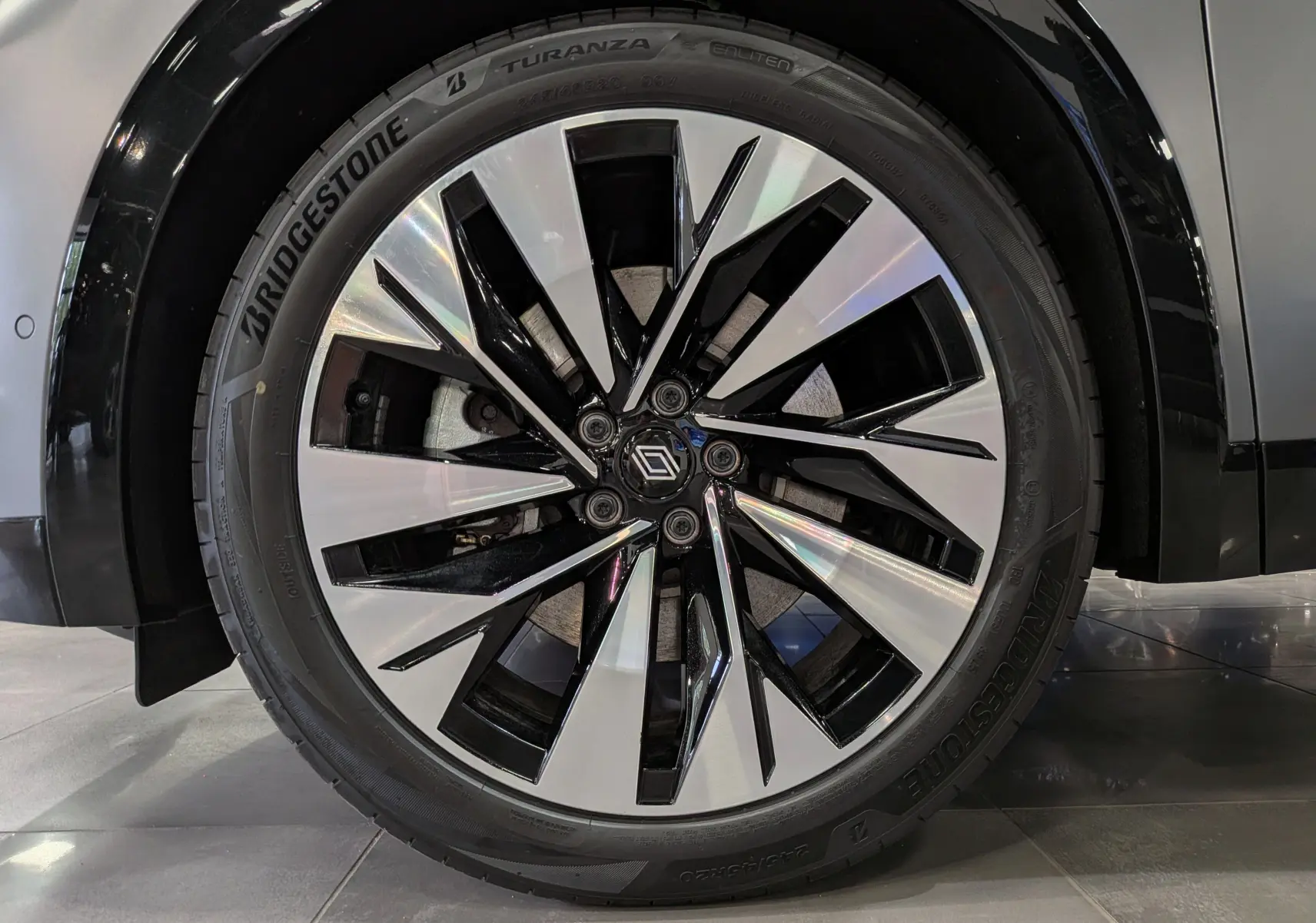 Gros plan sur la jante bicolore noire et argent du Renault Rafale gris schiste satin, mettant en valeur le logo central Renault.