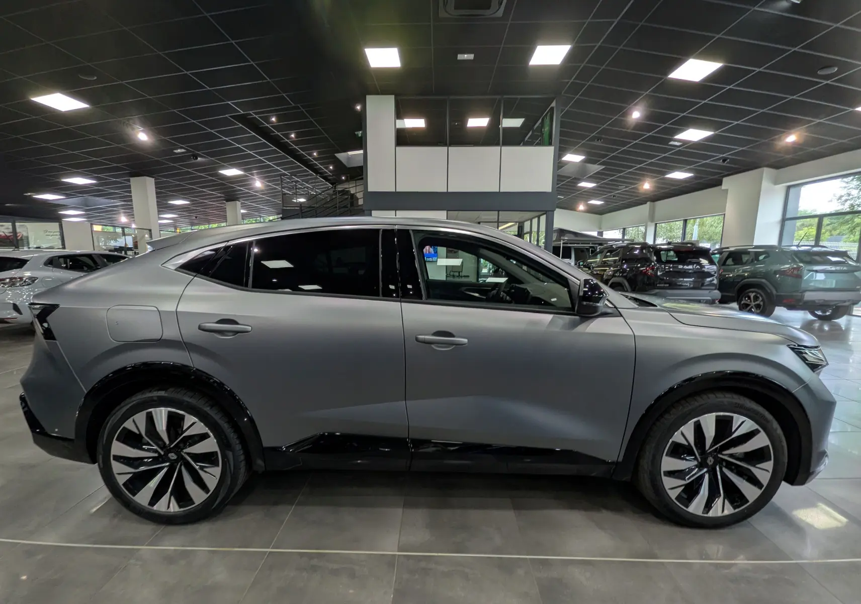 Profil côté gauche du Renault Rafale E-Tech gris schiste satin, soulignant ses jantes bi-ton et son design coupé SUV.