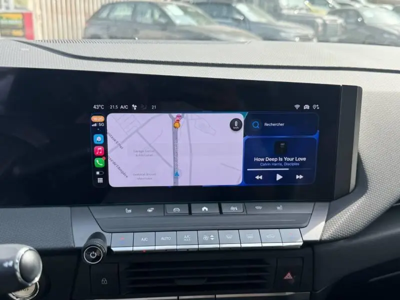 Vue intérieure du tableau de bord de l'Opel Astra 2024 gris, avec écran tactile affichant navigation et musique.