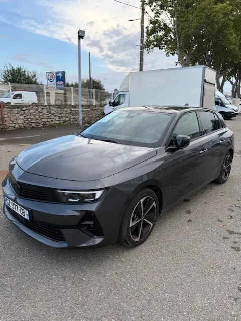 Opel Astra 1.5 Diesel gris vue 3/4 avant droit, avec jantes noires et calandre moderne, stationnée en extérieur.