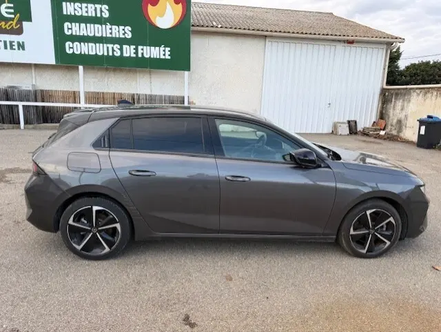 Vue de profil côté gauche d'une Opel Astra gris métallisé 2024, version 1.5 Diesel 130 ch avec jantes noires distinctives.