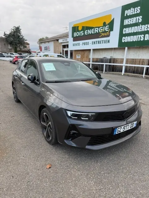 Opel Astra 1.5 Diesel gris 2024 vue 3/4 avant droit, avec calandre noire et jantes alliage sombres.