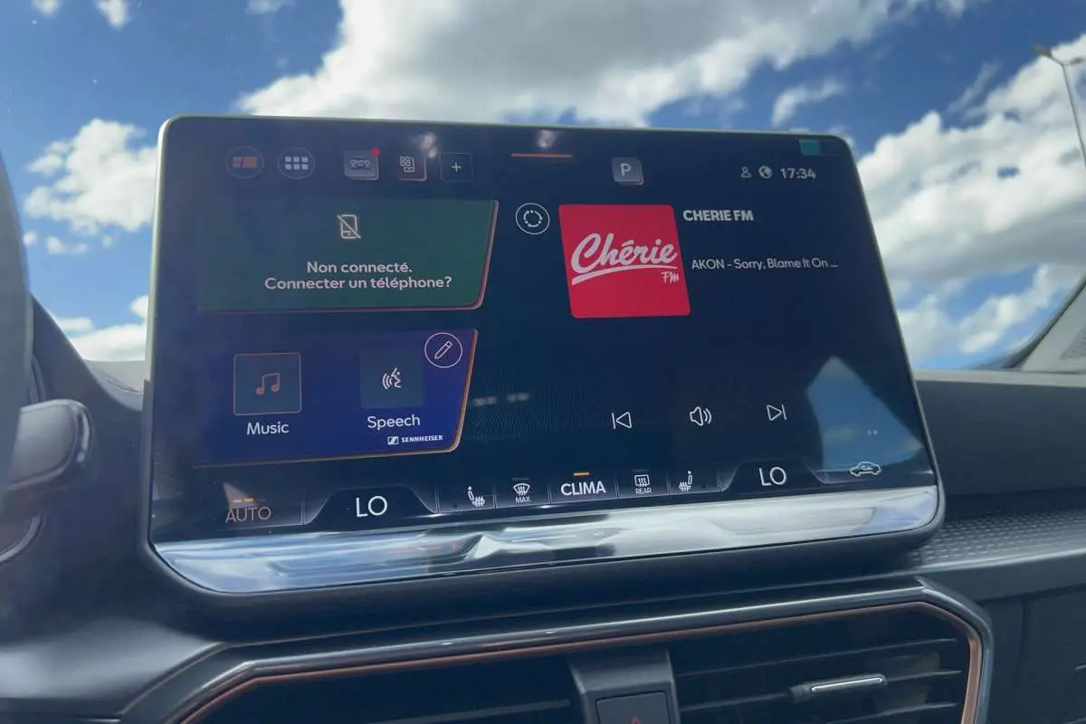 Écran tactile central du CUPRA Formentor noir minuit, affichant l'interface audio Chérie FM avec ciel bleu en arrière-plan.