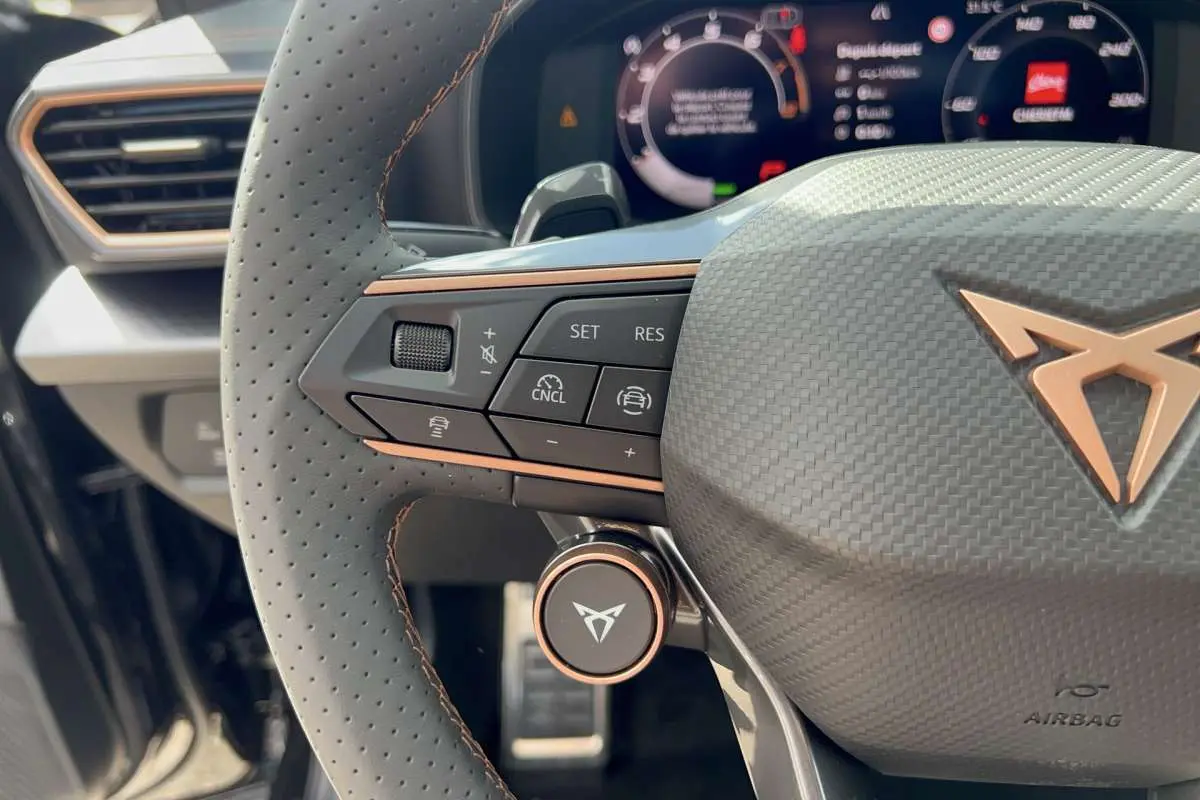 Gros plan sur le volant cuir perforé côté gauche de la CUPRA Formentor noir minuit avec commandes multifonctions et logo cuivre.
