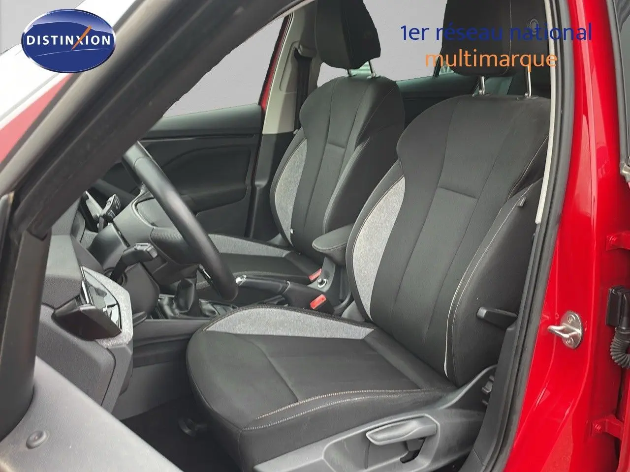 Vue intérieure côté conducteur d'un Skoda Kamiq rouge velvet metal, sièges tissu gris et noir avec coutures apparentes.