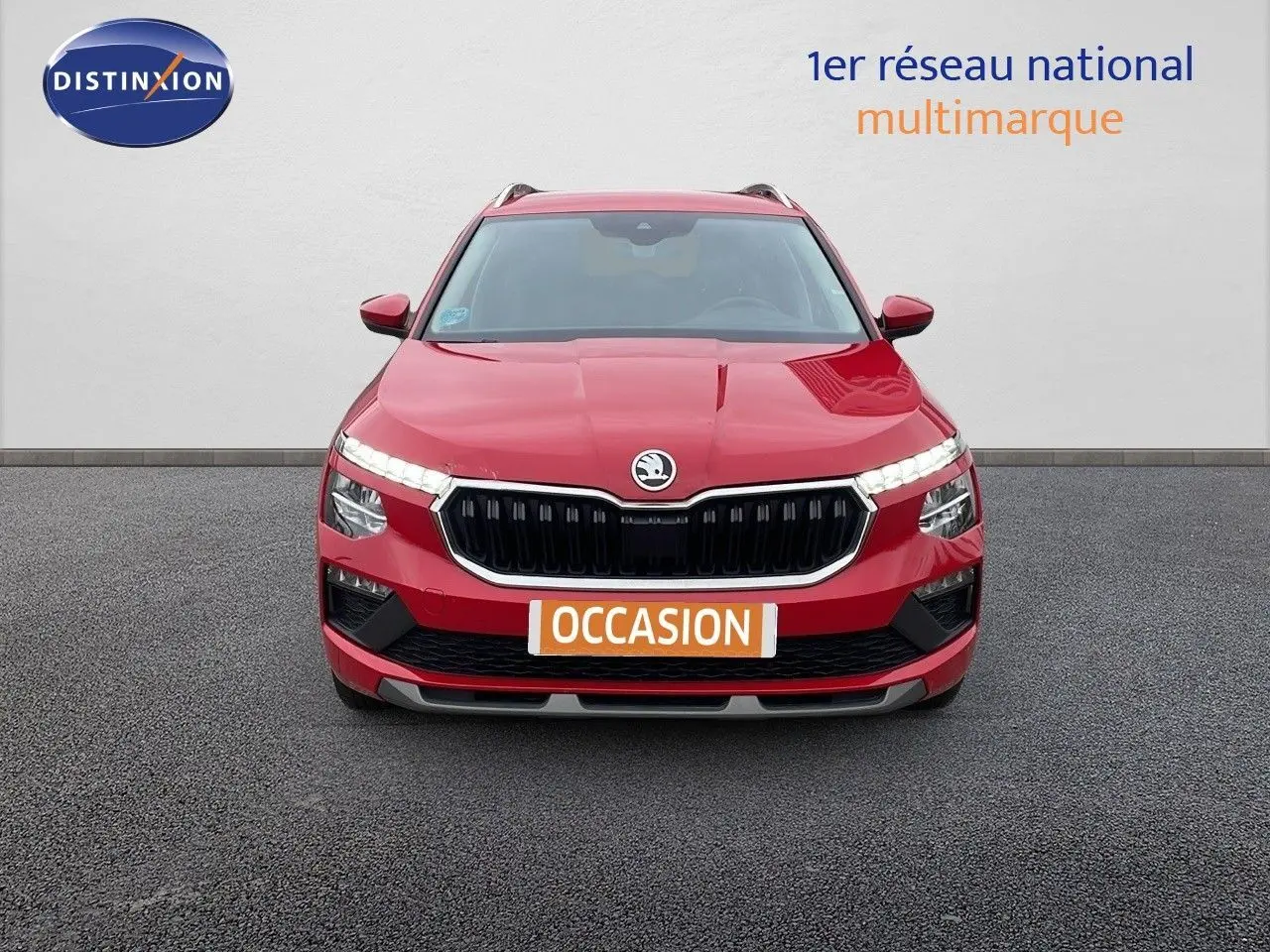 Vue avant d'un Skoda Kamiq rouge Velvet Metal avec calandre noire et feux LED allumés sur fond neutre.