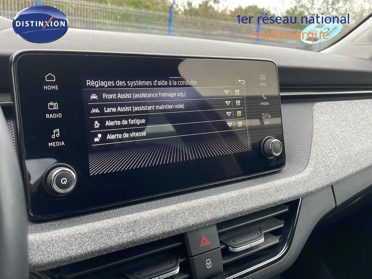 Écran tactile central du Skoda Kamiq 2024 affichant les réglages d'aide à la conduite, avec tableau de bord gris texturé.