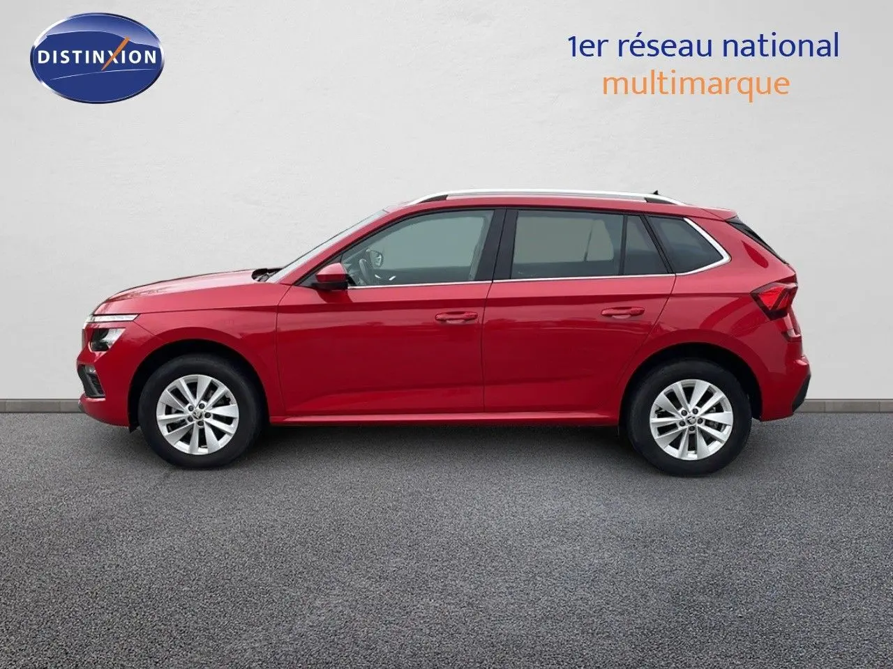 Profil droit d'un Skoda Kamiq 2024 rouge Velvet Metal, compact et moderne, sur fond neutre intérieur showroom.