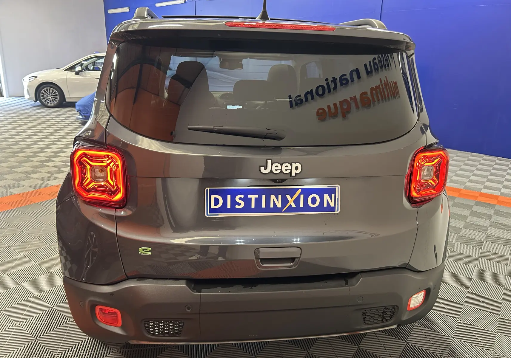 Vue arrière d'une Jeep Renegade gris graphite avec feux allumés dans un showroom.