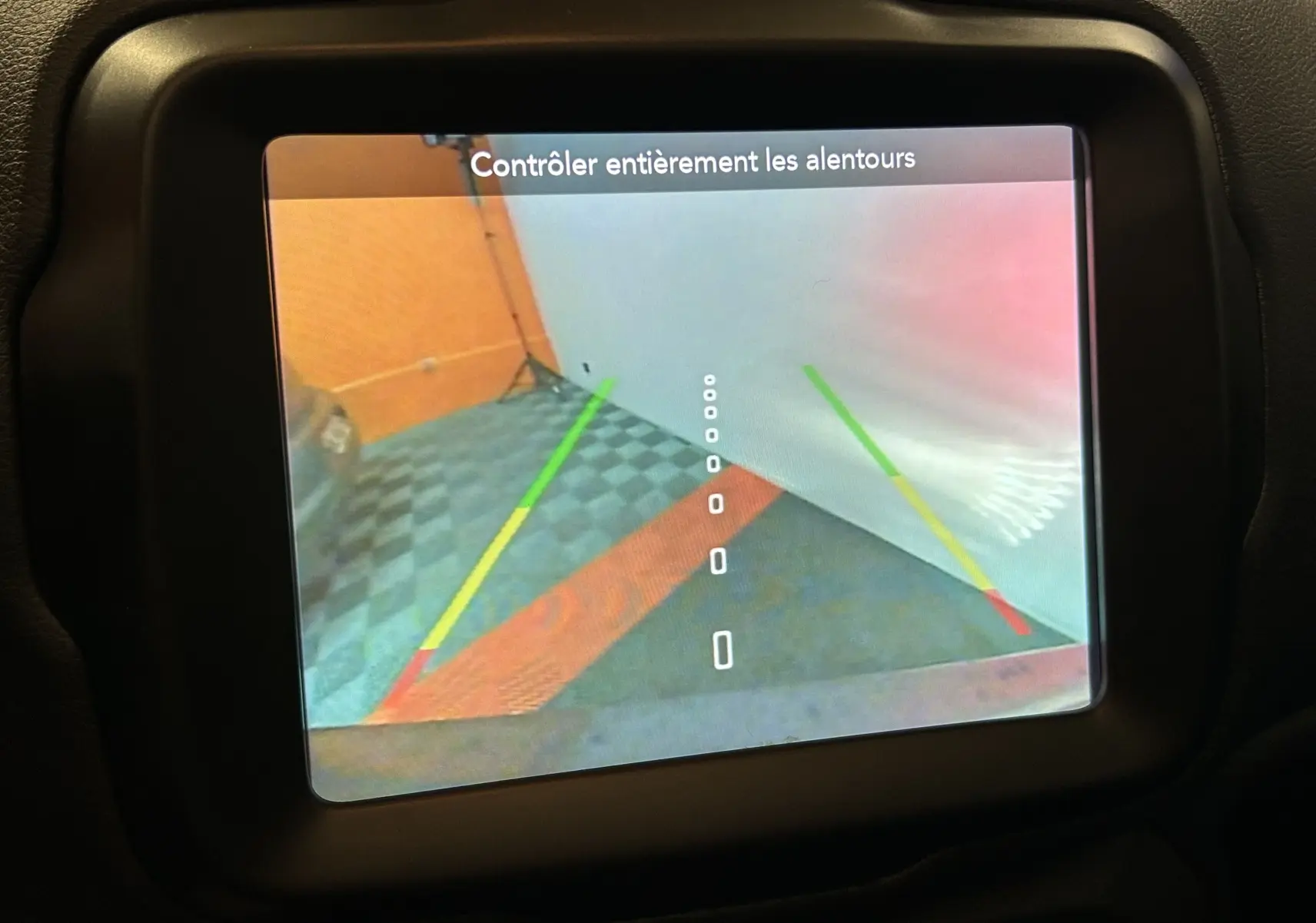 Écran de caméra de recul du Jeep Renegade 2023 affichant les lignes de guidage colorées et un mur orange en arrière-plan.