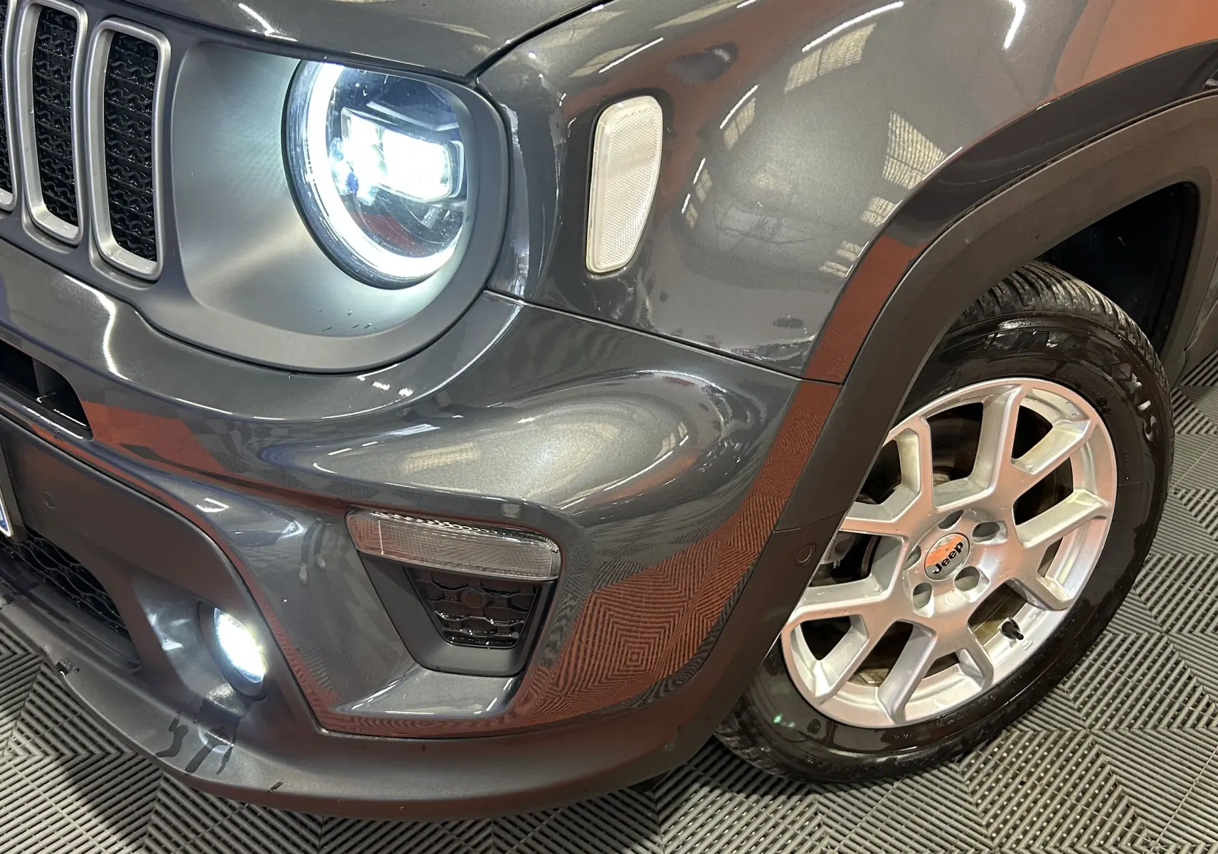 Gros plan sur l'avant droit du Jeep Renegade gris graphite 2023, mettant en valeur le phare LED allumé et la jante alu.