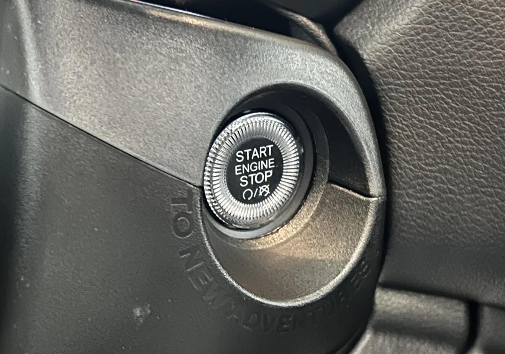 Gros plan sur le bouton Start Engine Stop entouré du marquage Jeep Renegade, intérieur noir du SUV gris graphite.
