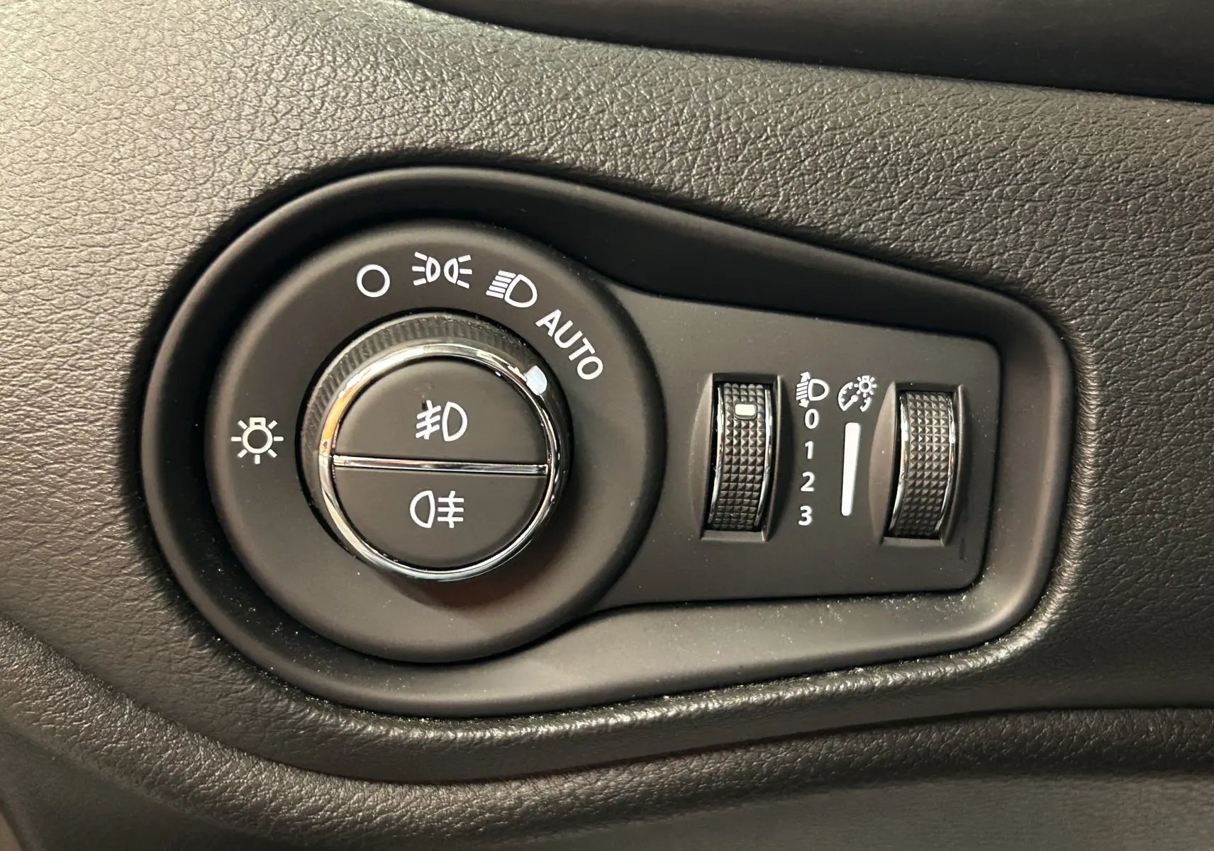 Gros plan sur les commandes d’éclairage noires du tableau de bord du Jeep Renegade Turbo T4 MHEV 130 Limited 2023.