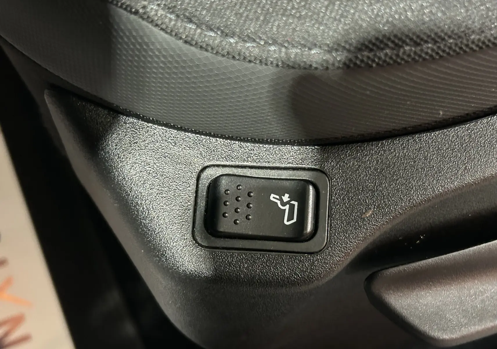 Gros plan sur le bouton de réglage électrique du siège côté conducteur dans l’habitacle gris foncé du Jeep Renegade 2023.